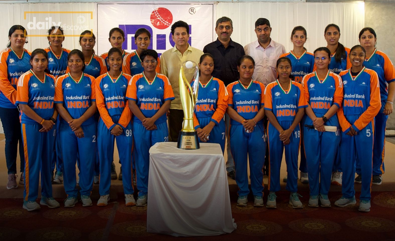 Sachin Tendulkar standing with the Indian visually challenged women's cricket team and the trophy